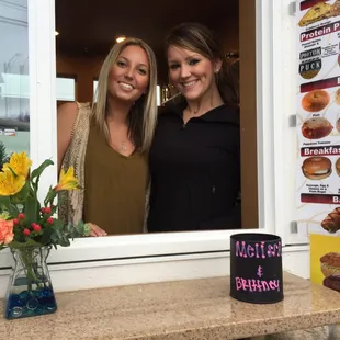 two women standing in front of a window