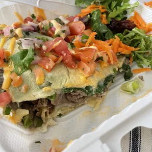 a burrito with a salad in a styrofoam container