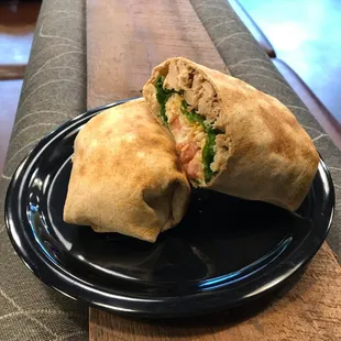 a burrito cut in half on a black plate