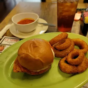 a burger and onion rings on a green plate