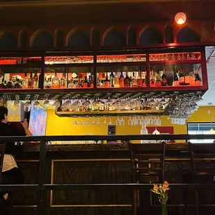 a bar with wine glasses on the shelves