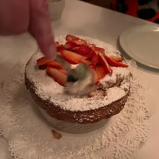 a person decorating a cake with strawberries