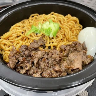 a bowl of noodles with meat and an egg
