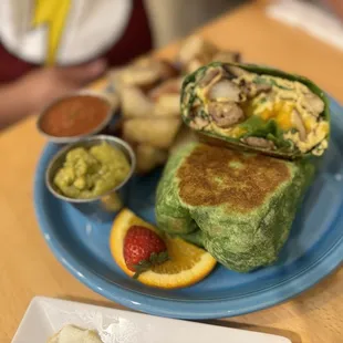Breakfast wrap w/ link sausage guacamole &amp; salsa and a side of potatoes.