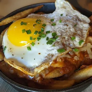 a fried egg on top of french fries