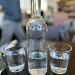 a bottle of water and two shot glasses