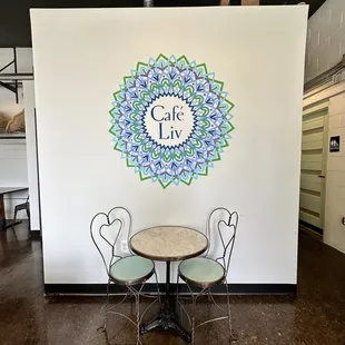 a table and chairs in front of a mural