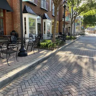 a brick sidewalk with tables and chairs