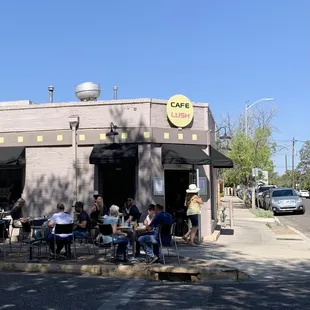people sitting at tables in front of a cafe