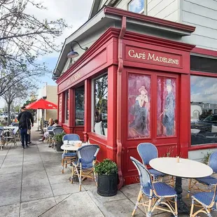 the outside of a cafe with tables and chairs