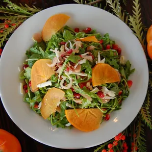 a plate of salad with persimmon and oranges