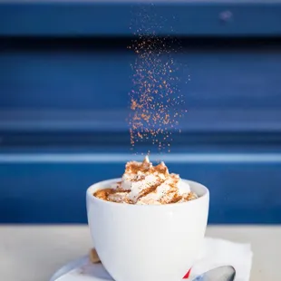 a person sprinkling sugar on a cup of coffee