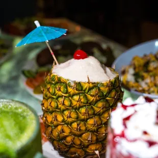 a pineapple with ice cream and a drink