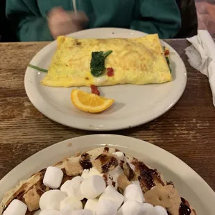 a plate of pancakes with marshmallows and an omelet