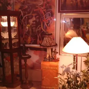 a corner of a room with a table, lamp, and pictures on the wall