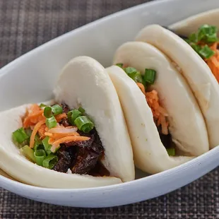 three steamed buns in a white bowl