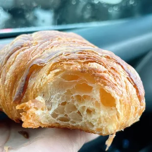 a hand holding a croissant pastry