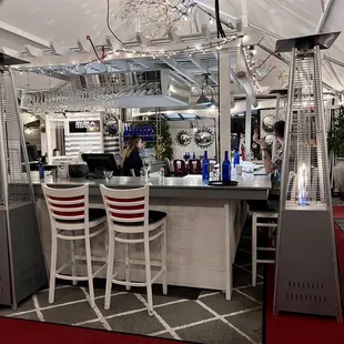 a bar with white chairs and a chandelier