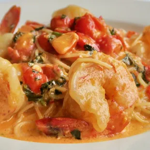 a plate of pasta with shrimp and tomatoes