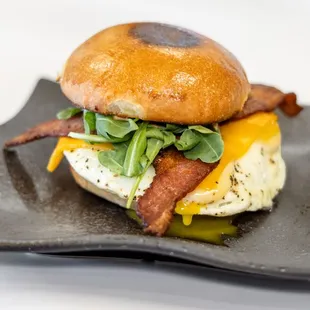 a bacon and egg sandwich on a black plate