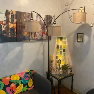 a corner of a living room with a couch, lamp, and picture on the wall