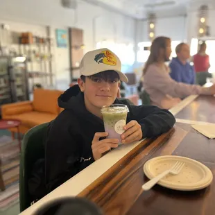 a woman sitting at a table with a cup of green tea