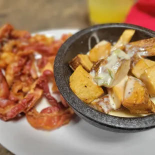 a bowl of potatoes, bacon, and gravy