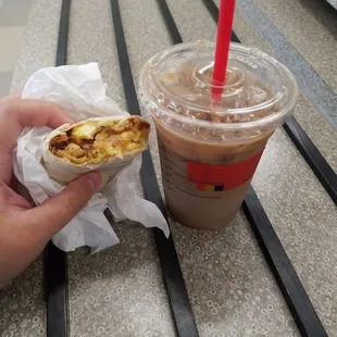 a person holding a sandwich and a drink