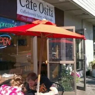 people sitting at tables outside a cafe