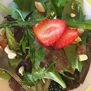 a plate of salad with strawberries and nuts