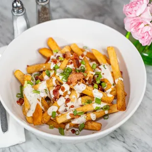 Decadent crisp golden French fries with home-made creamy ranch, diced bacon and green onion