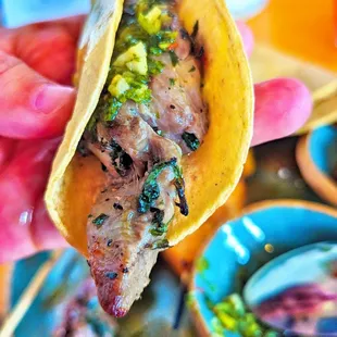 a hand holding a taco with meat and vegetables