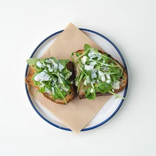 two pieces of bread with greens on a plate