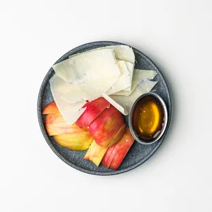 a plate of cheese, apples, and honey