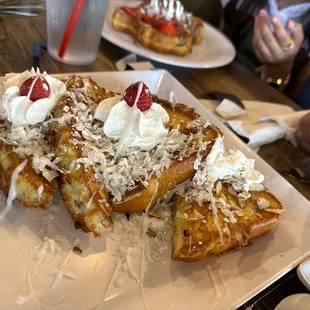 a plate of french toast with whipped cream and strawberries