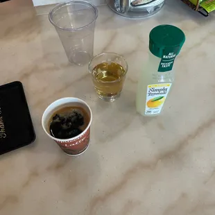 a cup of coffee, a bottle of coffee, and a drink on a table