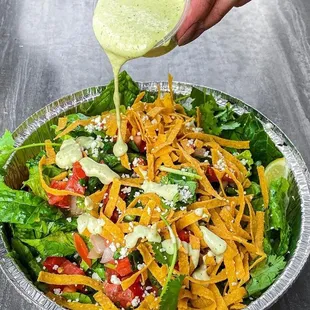 a salad being drizzled with dressing