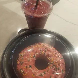 a pink donut with sprinkles and a drink