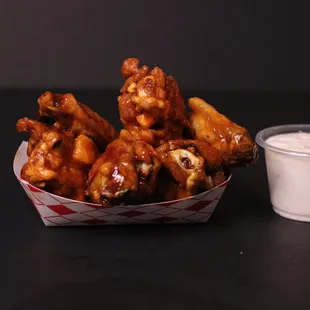 a basket of chicken wings and a cup of yogurt