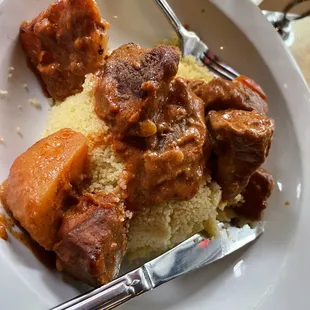 Beef stew dish with cous cous and sauce served on the side