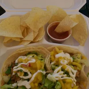 Tropical Tacos (2) in corn tortillas, with shredded pork, lettuce, cheese, mango salsa, and sour cream, served with chips and salsa!