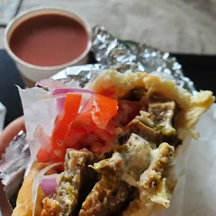 a hand holding a sandwich with meat and vegetables