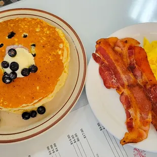 Blueberry pancakes with scramble eggs and bacon.