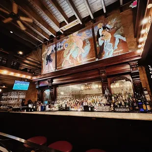 a bar with a mural on the wall