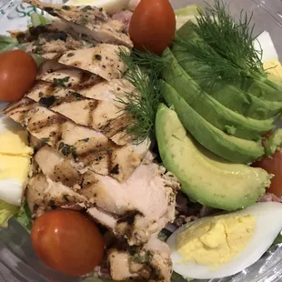 a salad with chicken, avocado, tomatoes and hard boiled eggs