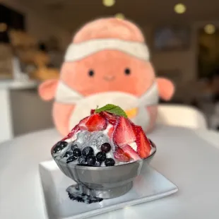 a bowl of ice cream with strawberries and blueberries