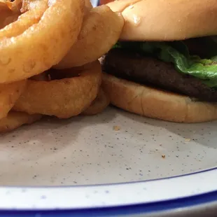 Close up of the USA Old Fashioned Burger and side of Onion Rings--half pound burger, lettuce, tomato, dill pickle slices, red onion.