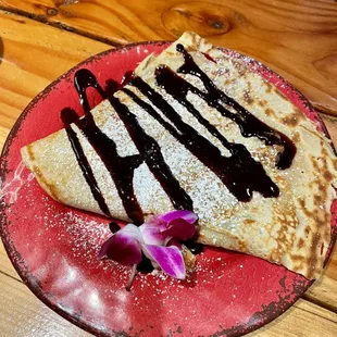 a crepe with chocolate sauce and a flower