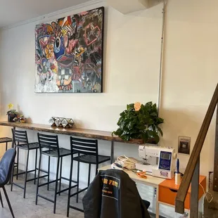 a dining area with bar stools and a painting on the wall