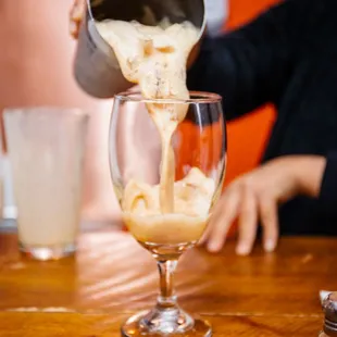 a person pouring coffee into a glass